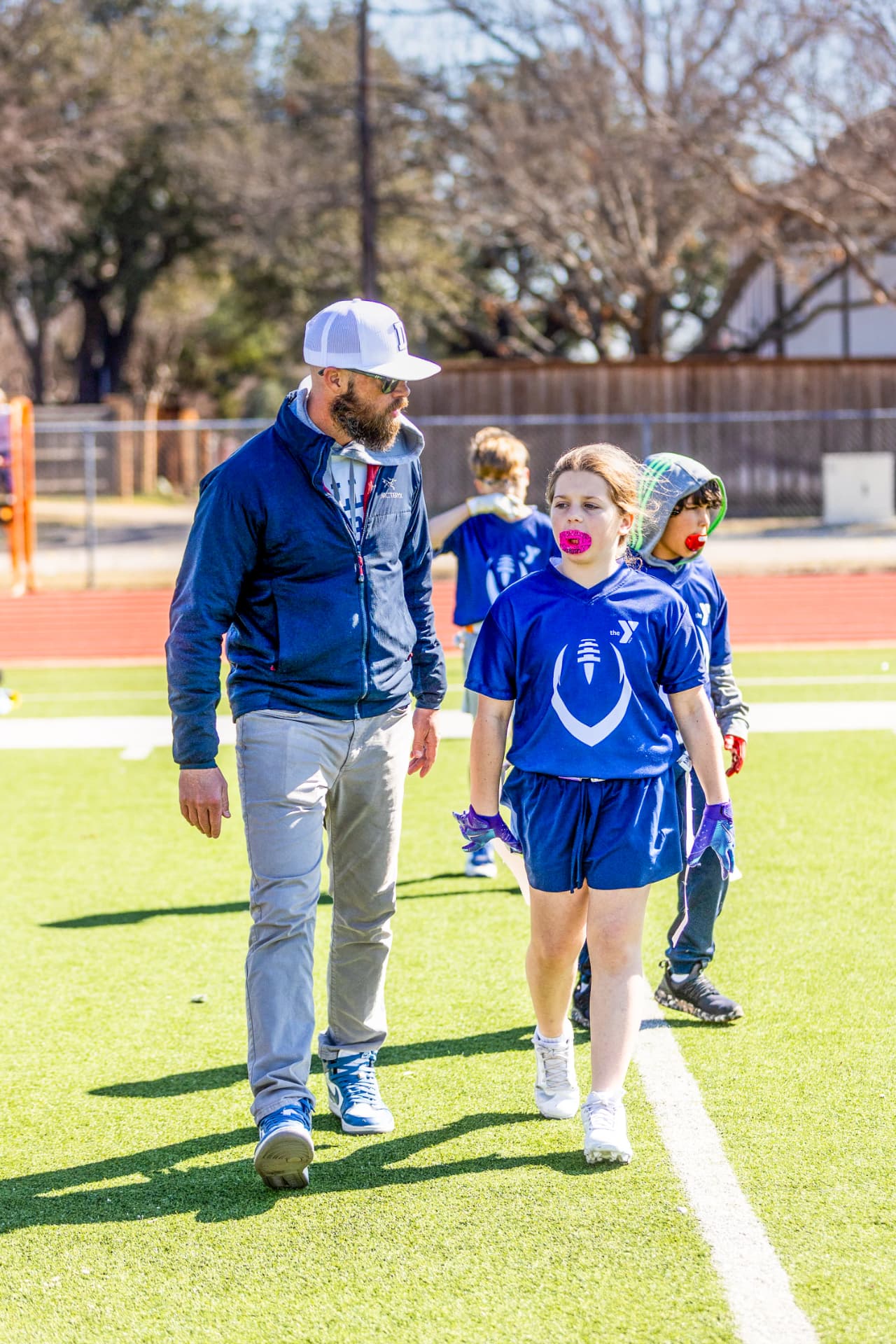 Coach walking with youth flag football players