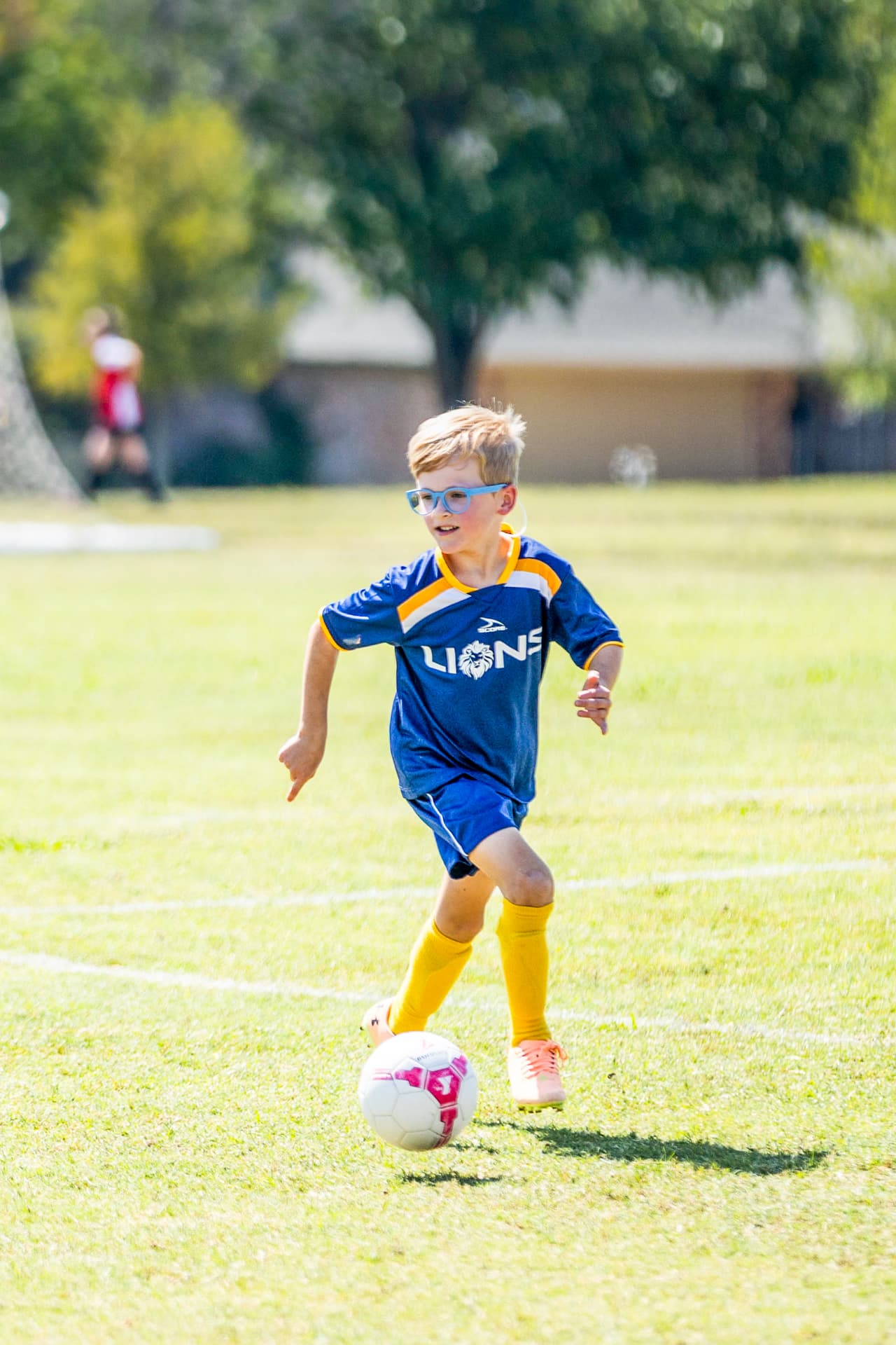 Young soccer player dribbling in blue glasses