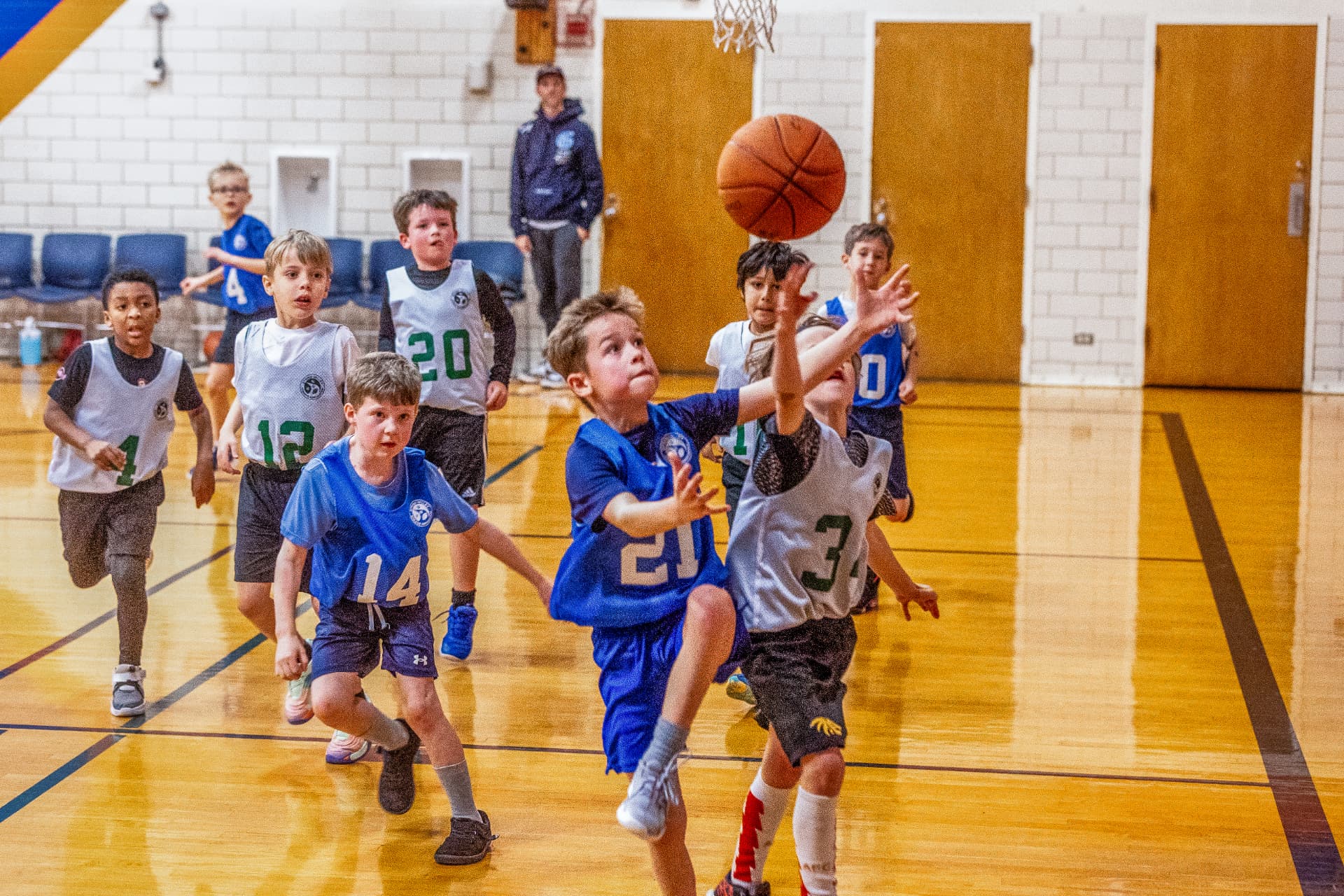 Youth basketball players chasing a loose ball in the gym