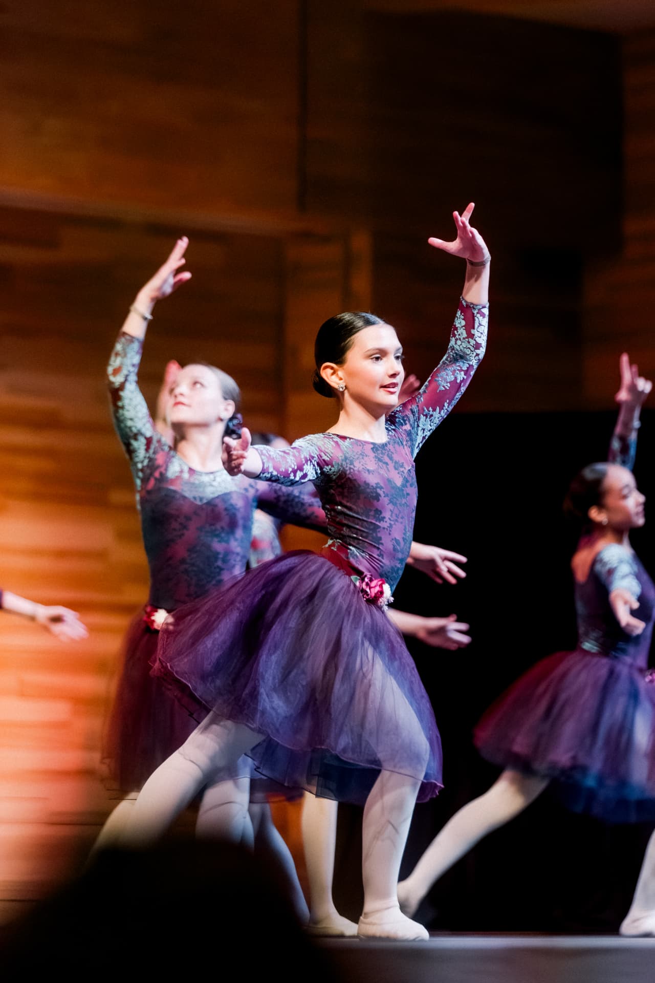 Young dancers performing in purple costumes on stage