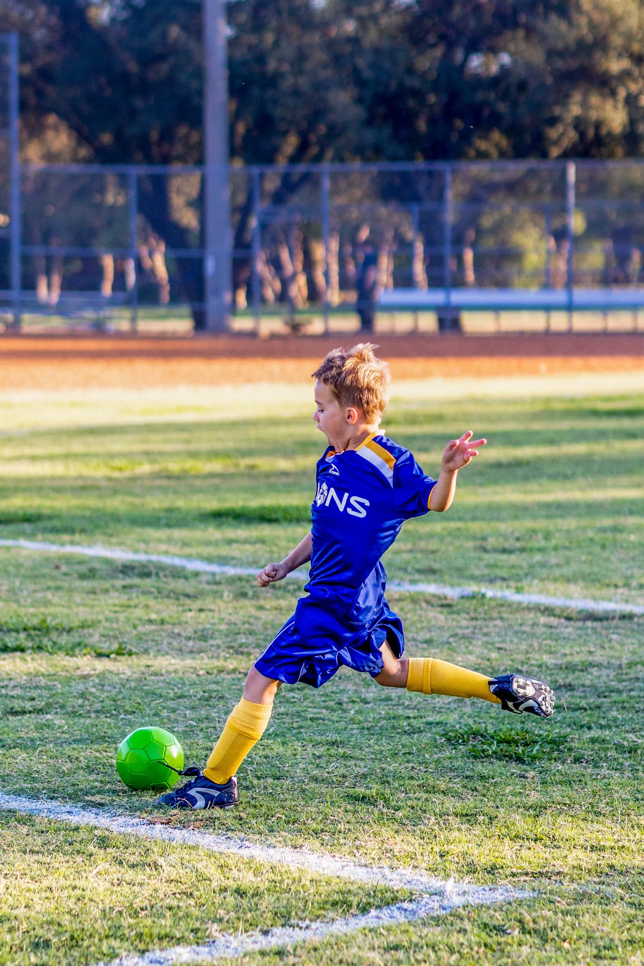 Young soccer player striking a green ball