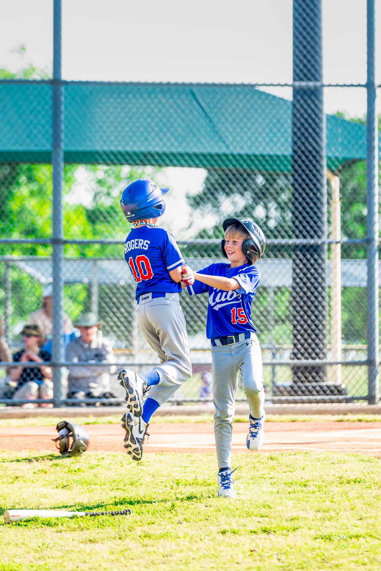 Two young baseball players jumping to celebrate with a high-five